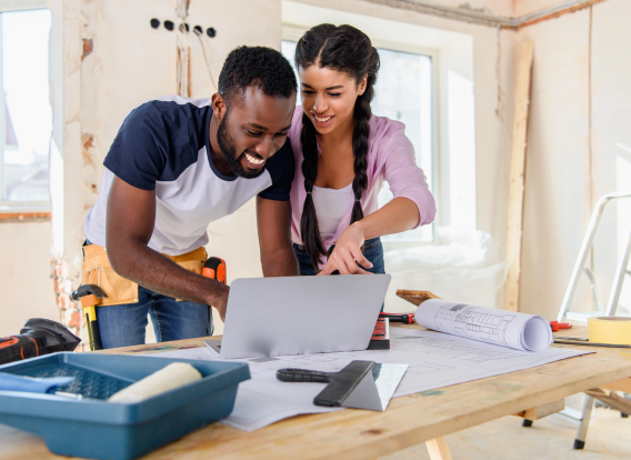 young african american woman pointing at laptop screen to boyfriend during renovation of home